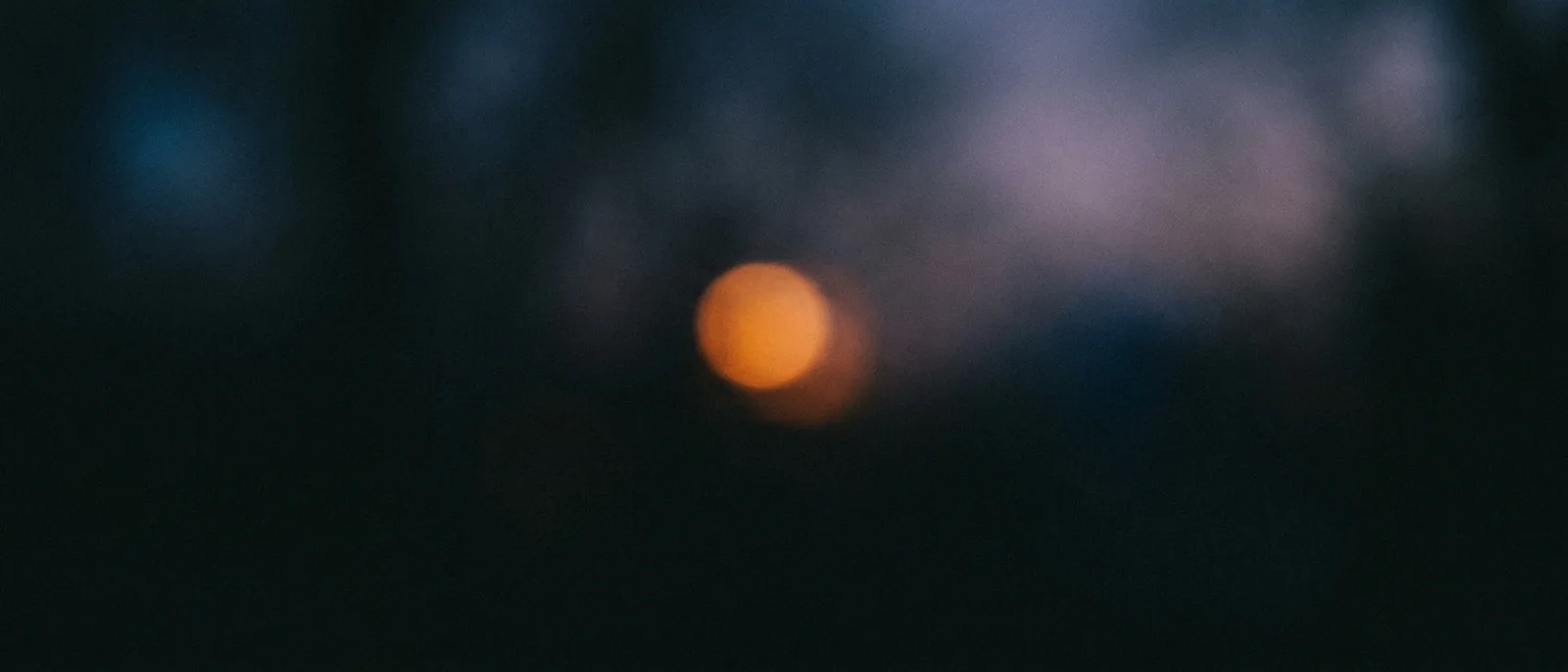A soft, out-of-focus ember of light dissolving in the dark, the quiet transition to sleep